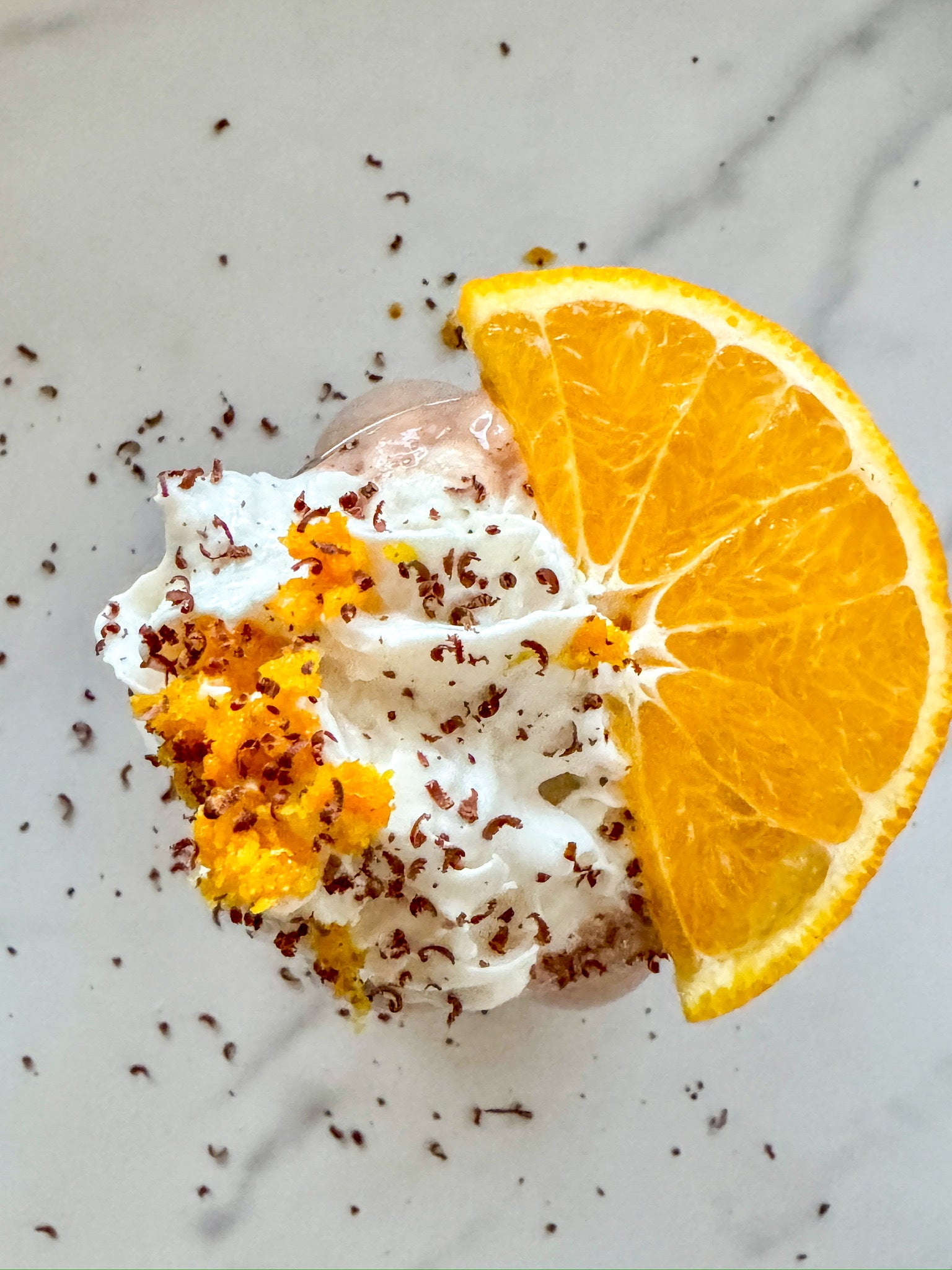 top shot of orange-chocolate smoothie with whipped cream and an orange slide