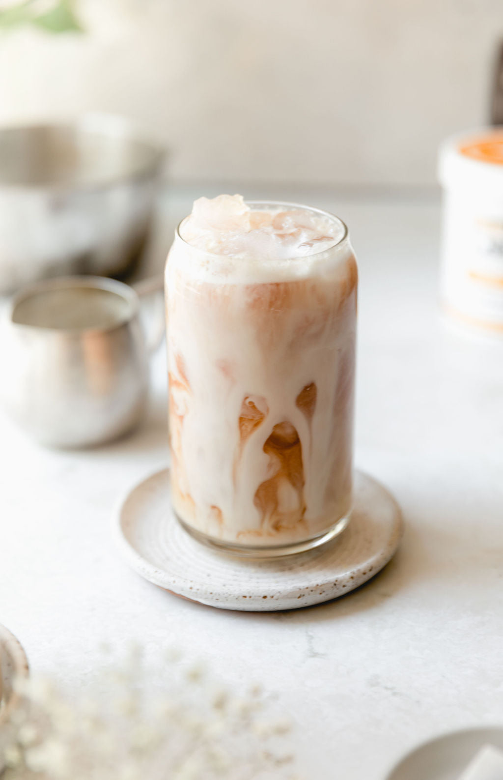 A tall glass of Iced English Breakfast Tea Latte, made with JOI plant base, sits on a ceramic coaster.