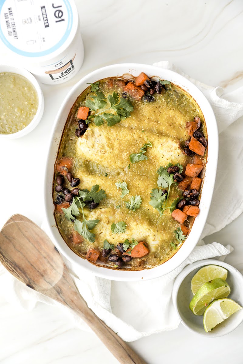 Creamy Jackfruit Enchiladas with salsa verde, black beans, sweet potato, and cilantro, served with lime wedges and JOI plant bases.