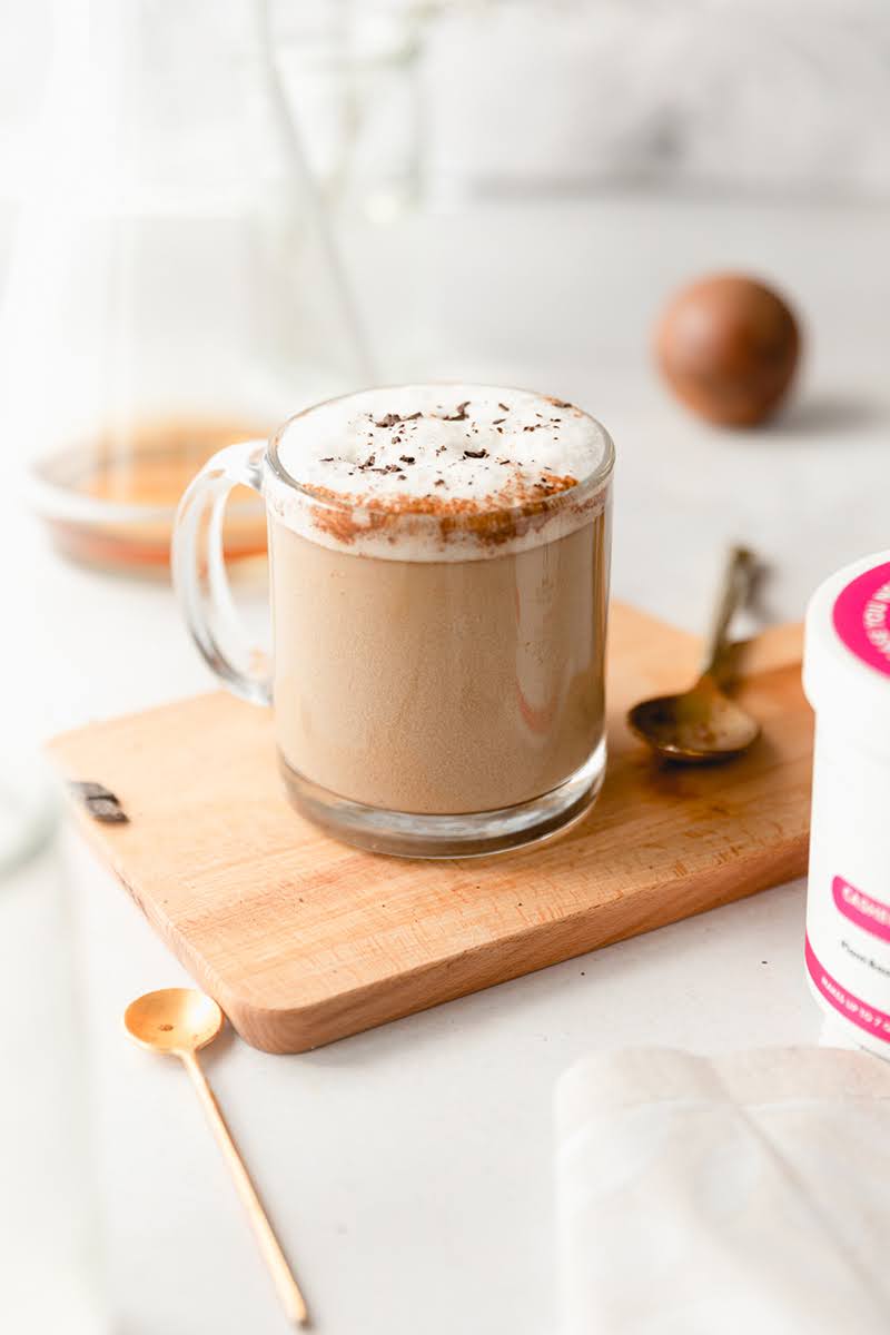 A festive gingerbread latte made with JOI plant base sits on a wooden board, topped with frothy milk and spices.