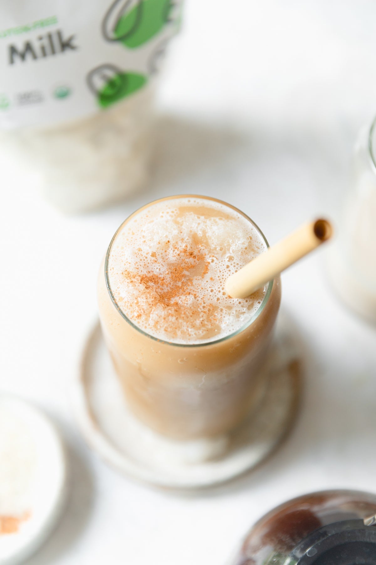 A tall glass of Blended Iced Coffee made with JOI plant base, topped with foam and cinnamon, with a bamboo straw.
