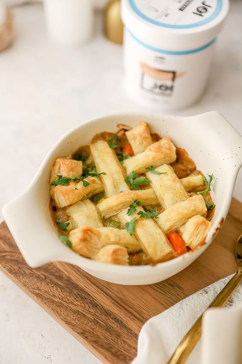 A vegan loaded veggie pot pie, topped with a golden lattice crust and fresh parsley, made with JOI plant base.
