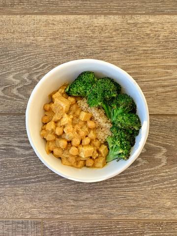 A bowl of Yellow Squash Curry with Coconut, featuring chickpeas and tofu, served with broccoli and quinoa.