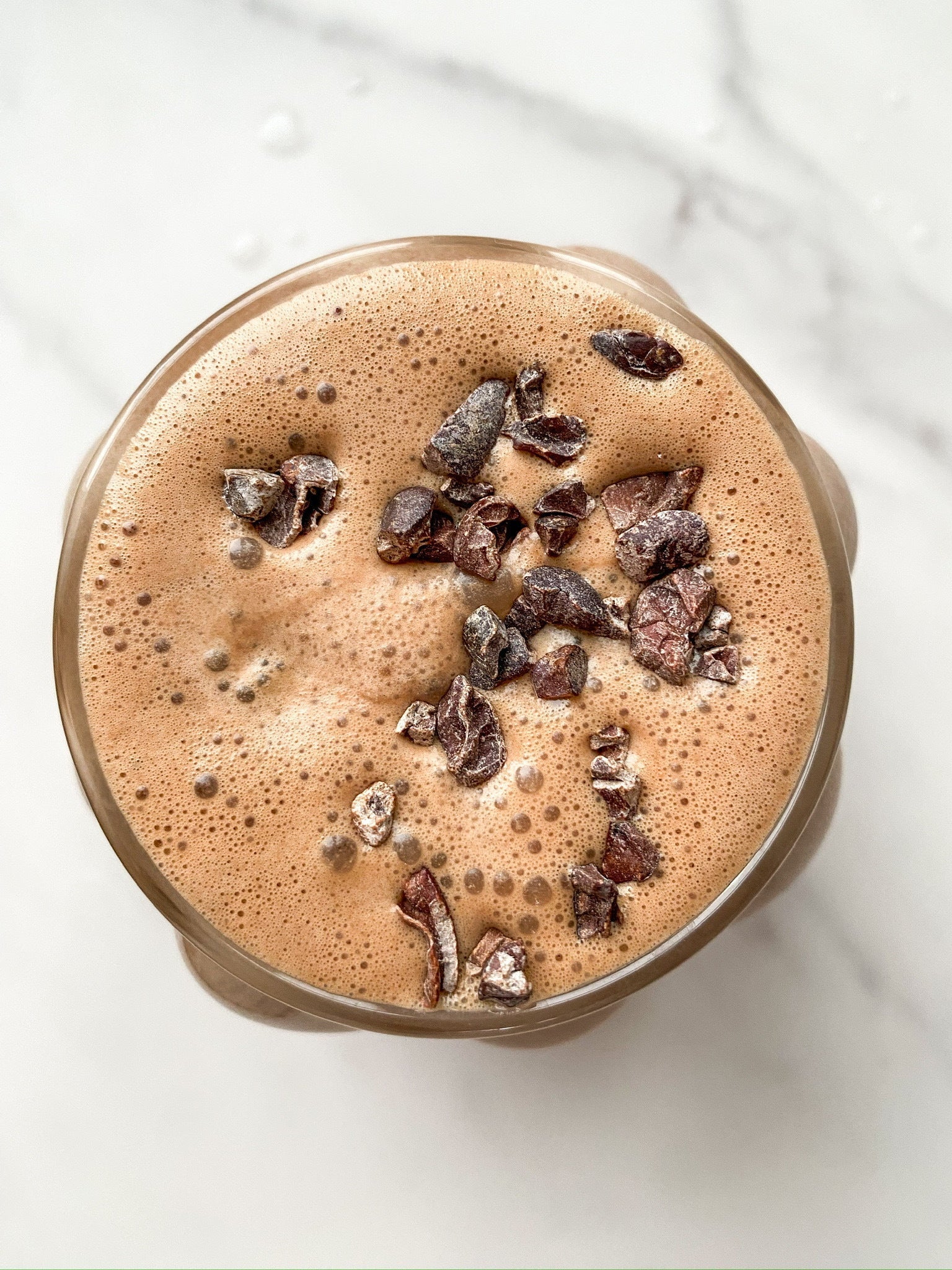 A JOI chocolate milk or frozen hot chocolate with cocoa nibs on top, seen from directly above.