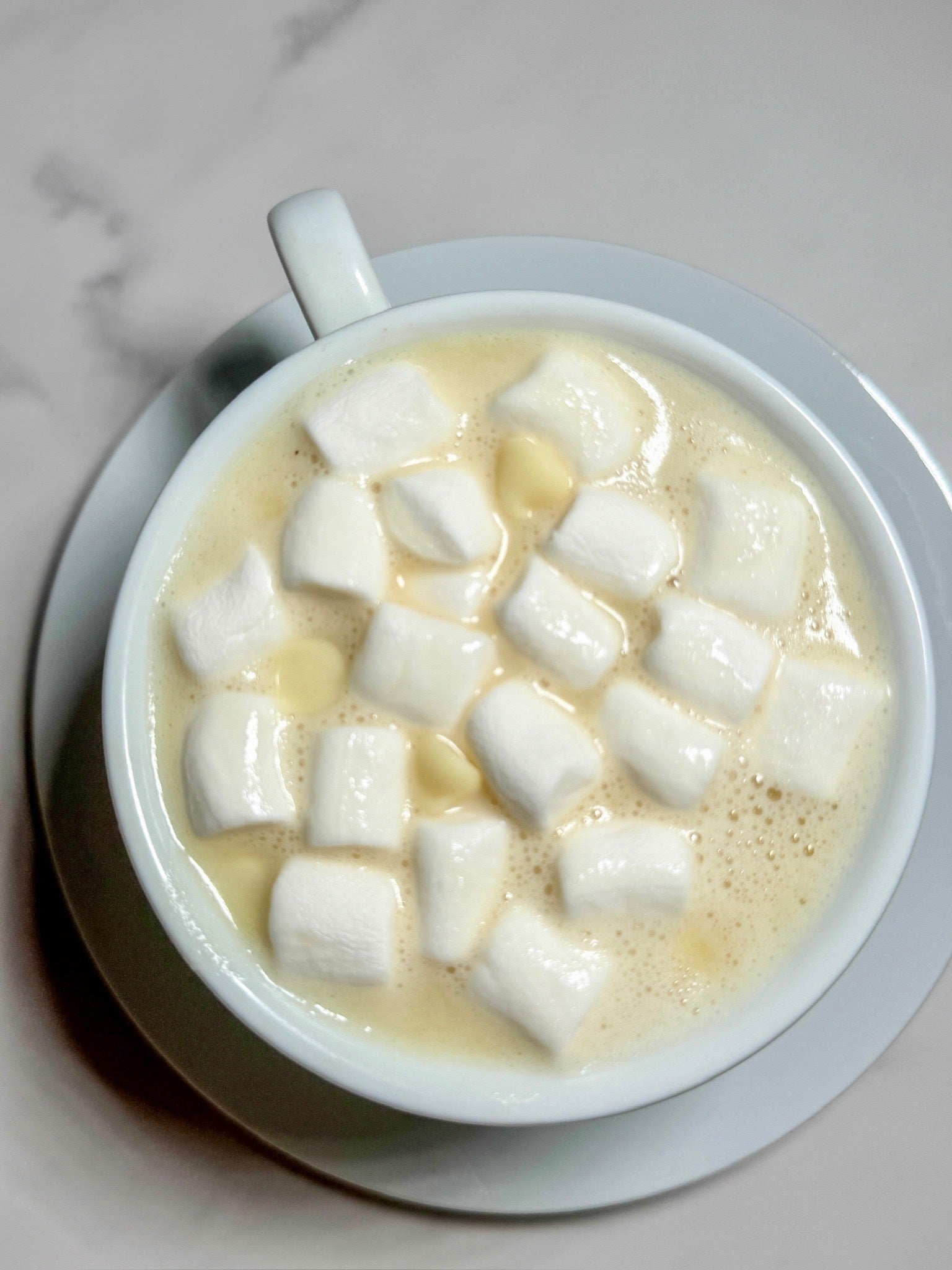 A warm cup of creamy dairy-free white hot chocolate made with JOI Almond Milk Powder, topped with marshmallows.
