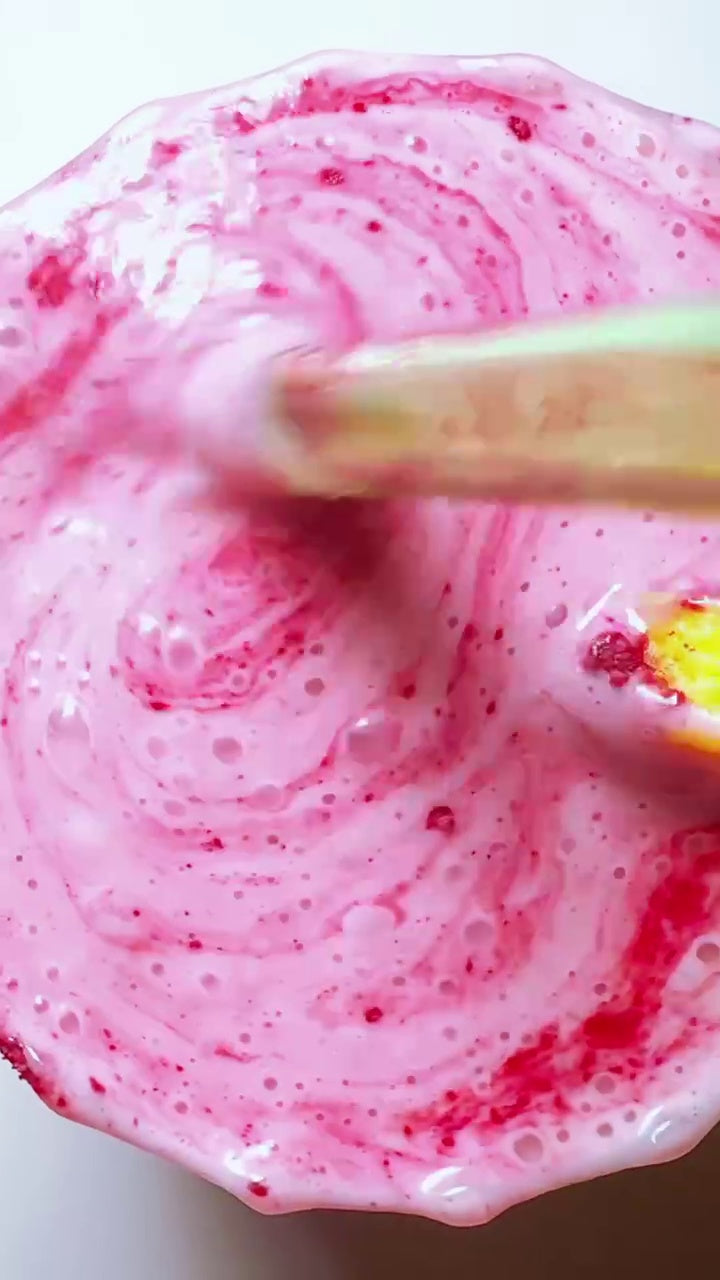 A vibrant, swirling pink JOI raspberry-strawberry lemonade with visible berry bits is being stirred.