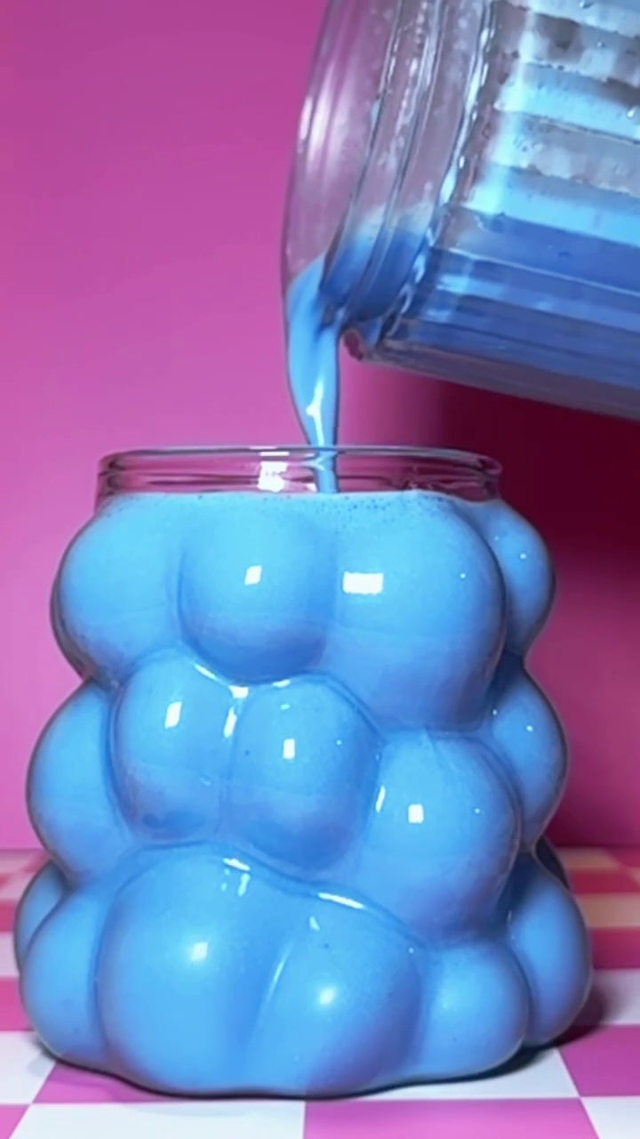 blue colada smoothie being poured from a personal blender into a glass