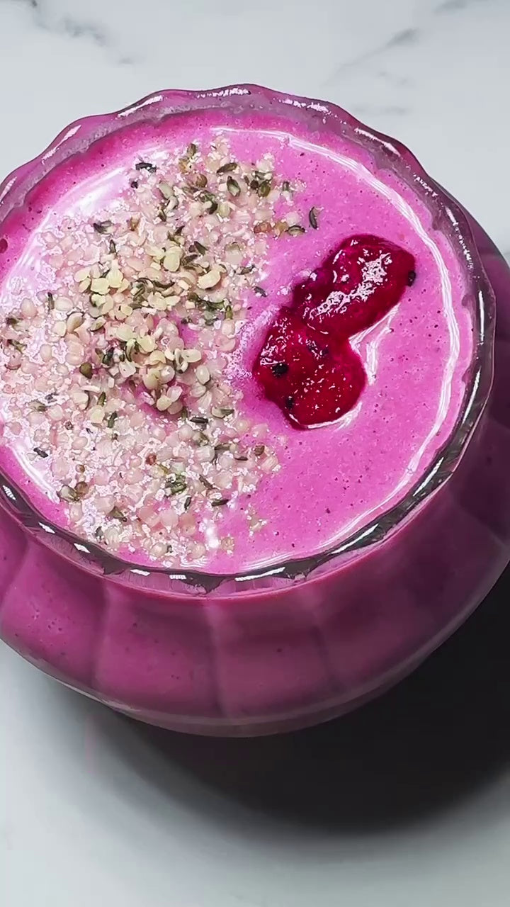 A vibrant pink Dragonfruit Berry Smoothie made with JOI, topped with hemp seeds and a swirl of fruit puree.