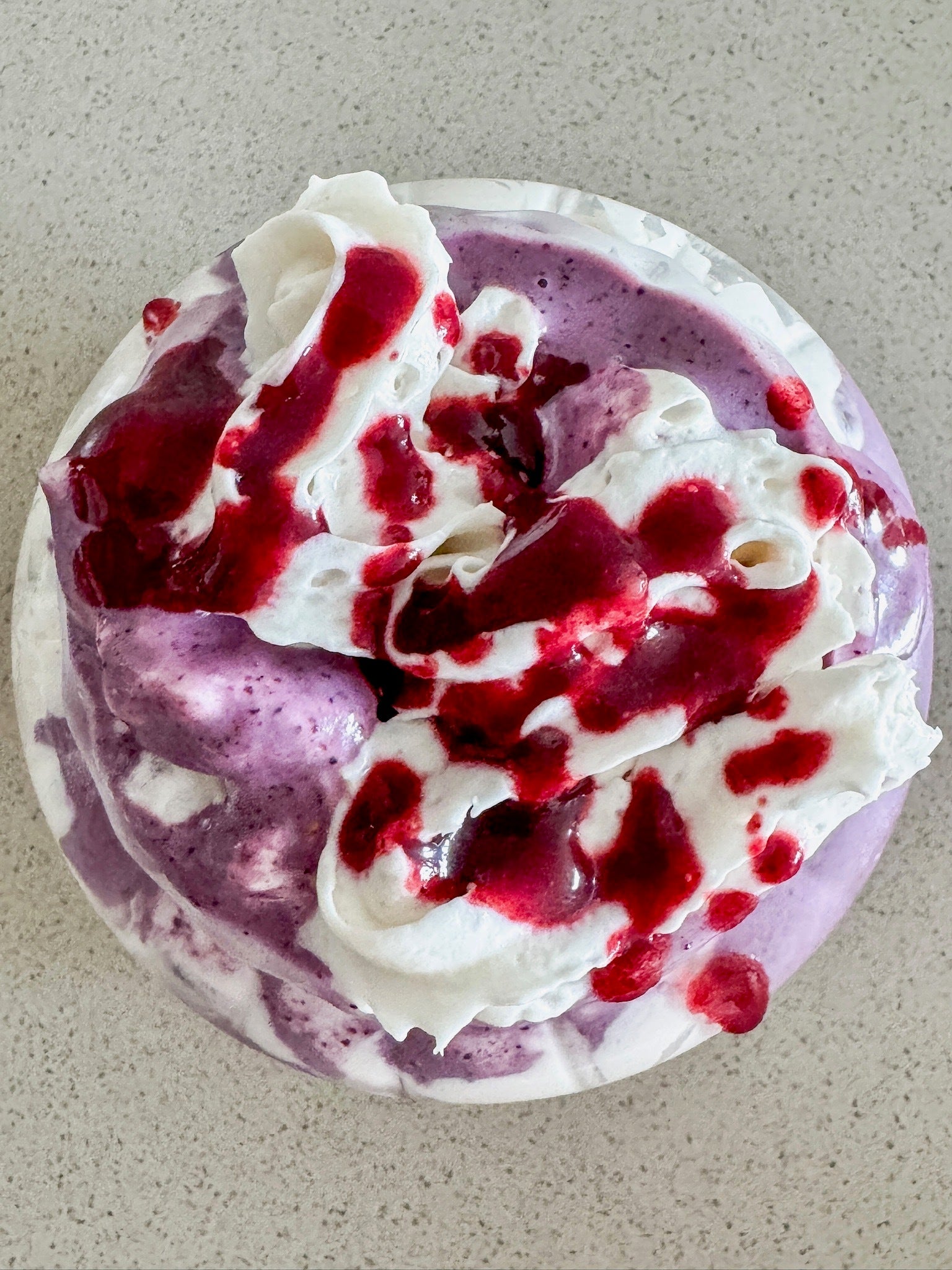 A Berry Chantilly Smoothie made with JOI, topped with white whipped cream and drizzled with a rich red berry sauce.