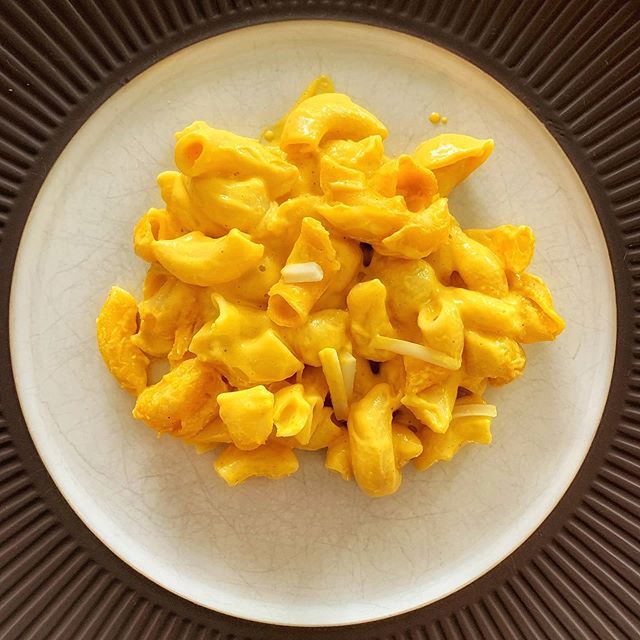 A creamy yellow macaroni and cheese, made more nutritious with JOI plant bases, sits on a white plate with a dark rim.