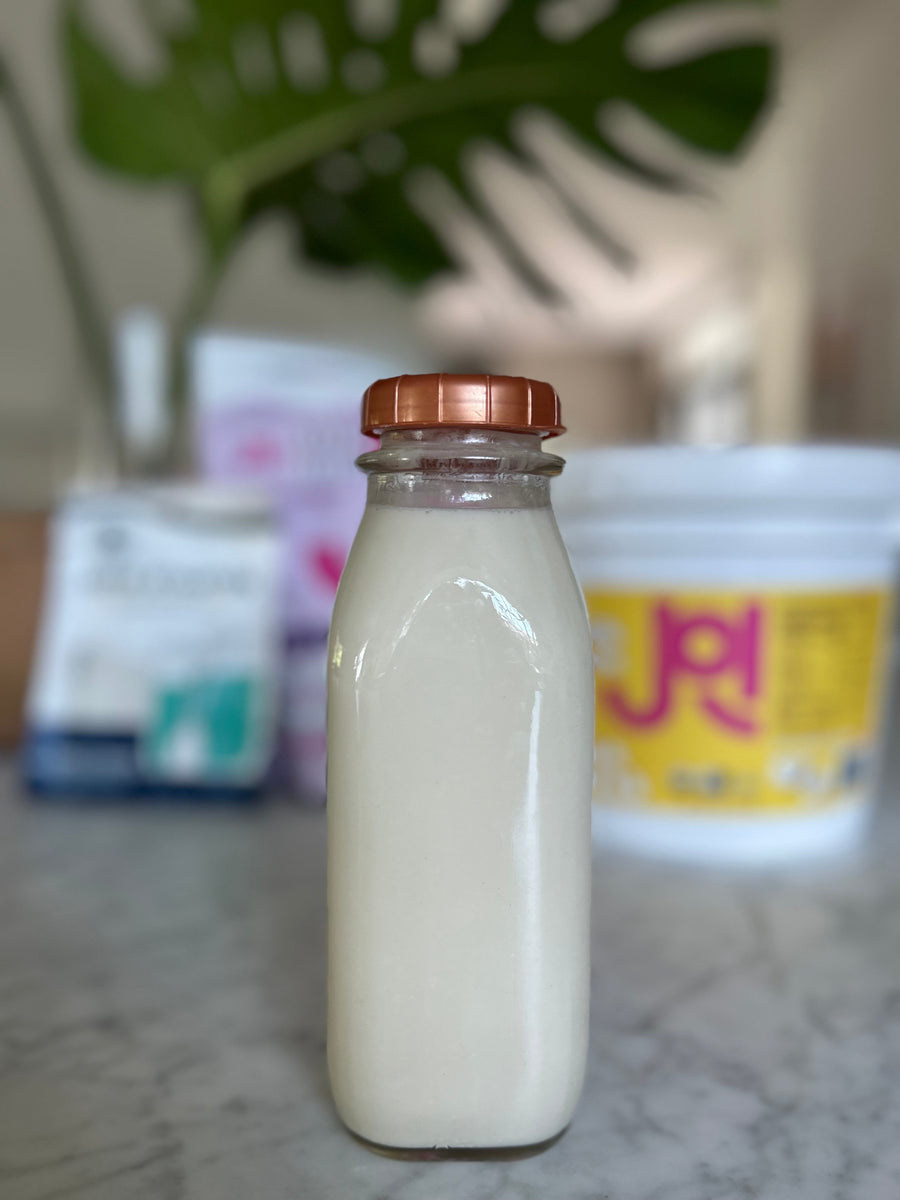 A glass bottle of homemade plant-milk kefir, made with JOI plant bases, sits on a counter with other ingredients.