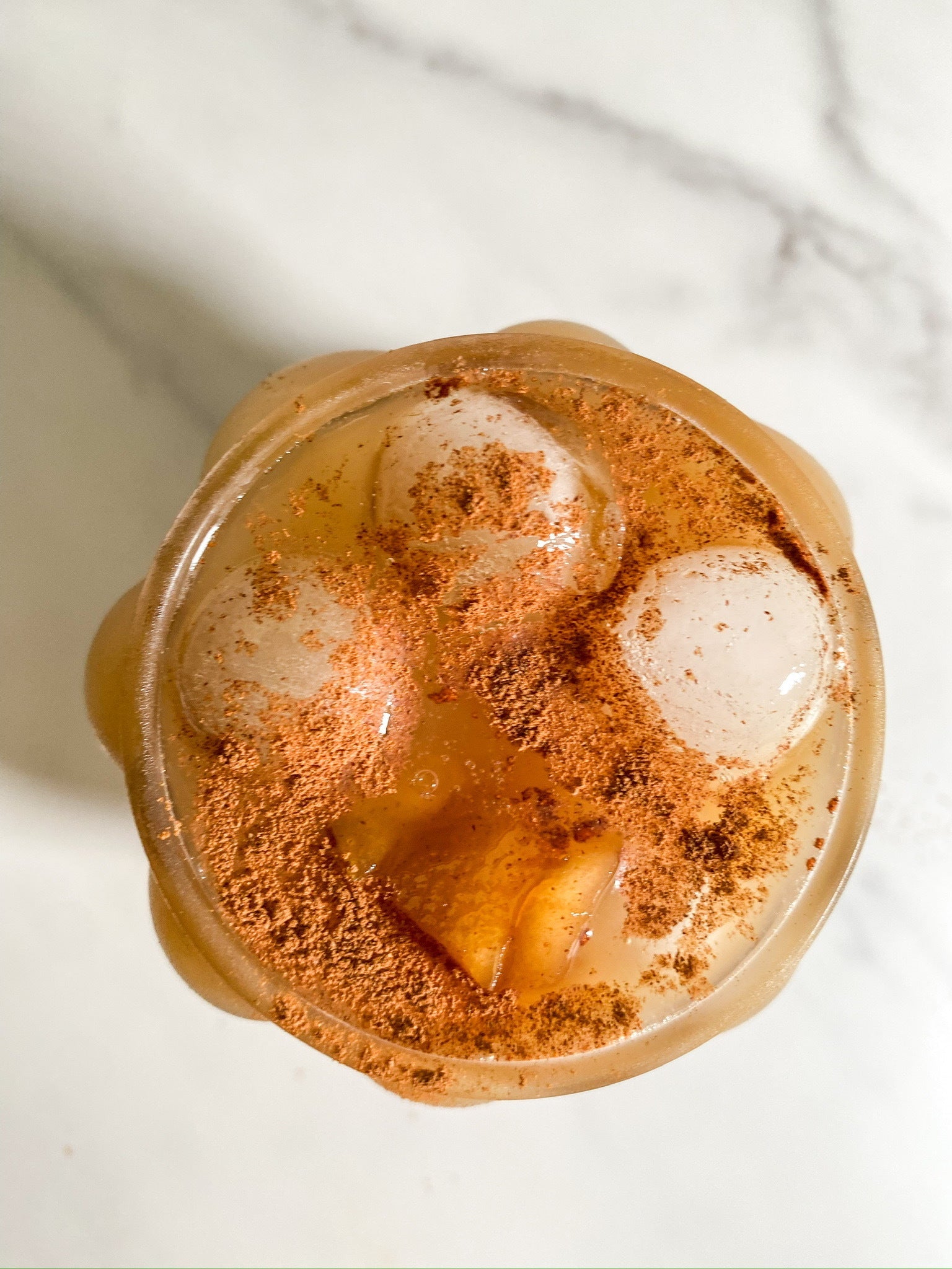 An overhead shot of a creamy Iced Apple Shaken Espresso made with JOI, topped with ice and sprinkled with cinnamon.