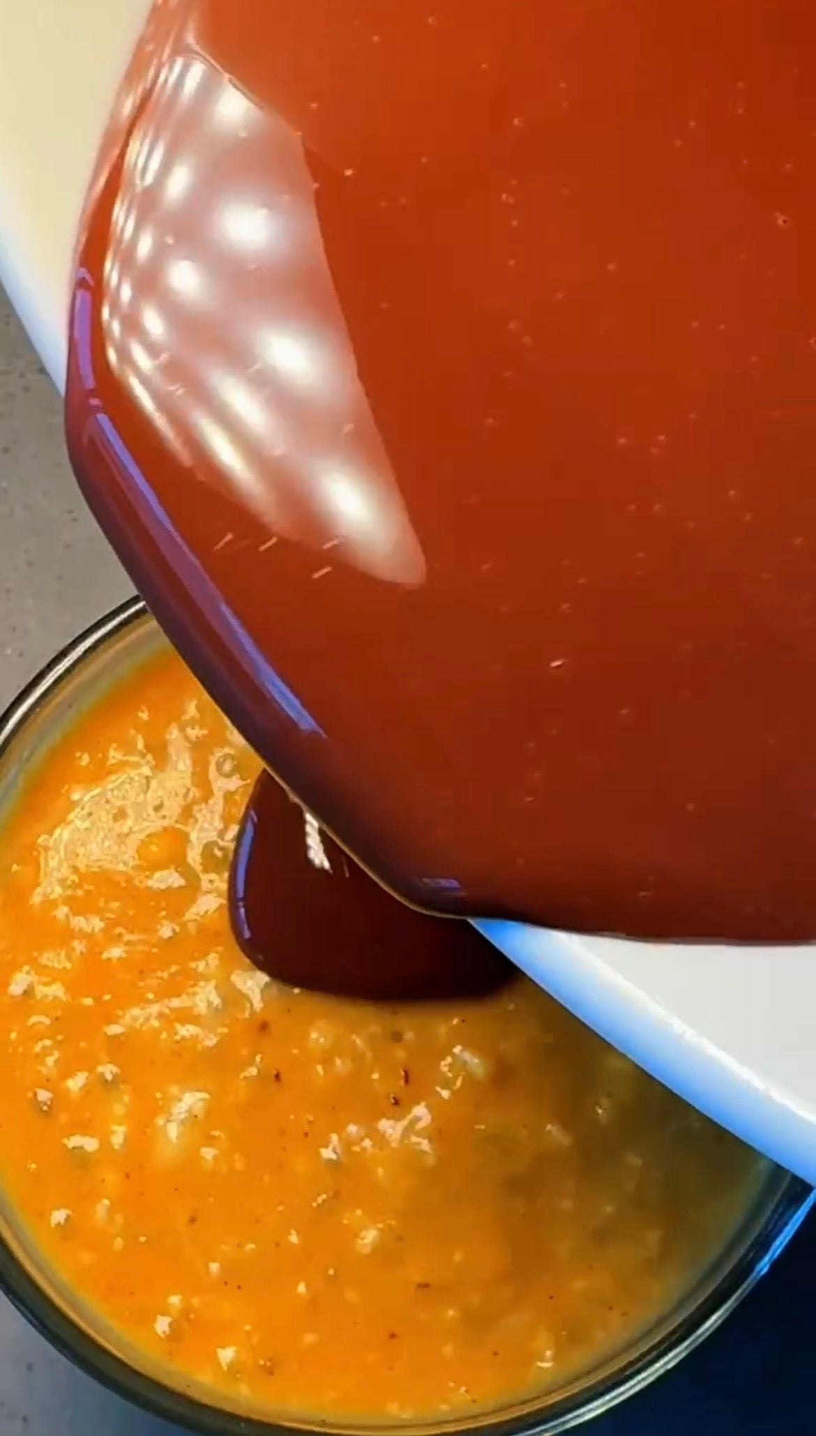 Warm, chocolate pumpkin spice oats are being poured from a white bowl into a glass bowl with a JOI plant base.