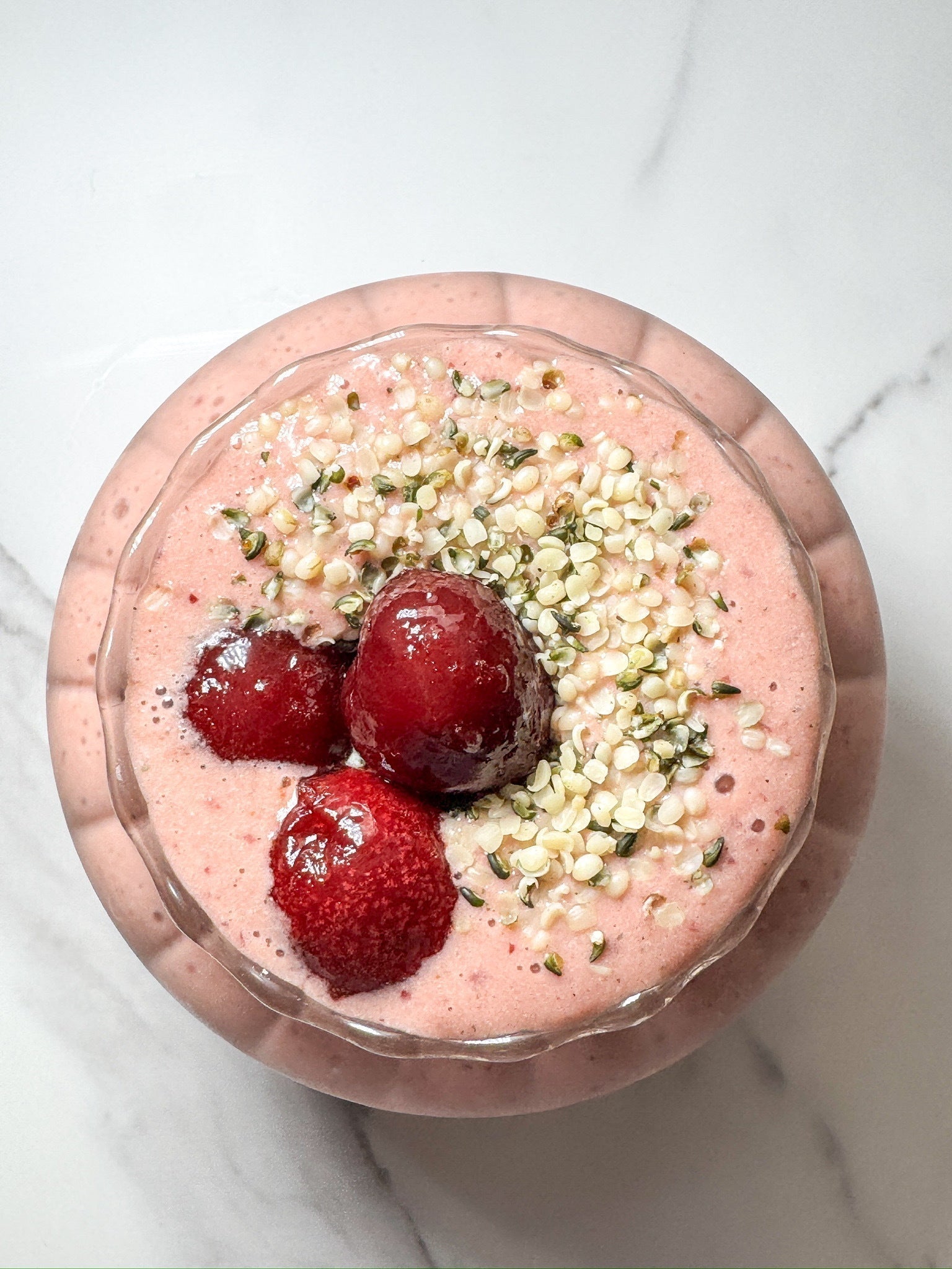 A vibrant mango cherry smoothie, made with JOI plant milk concentrate, is topped with strawberries and hemp seeds.