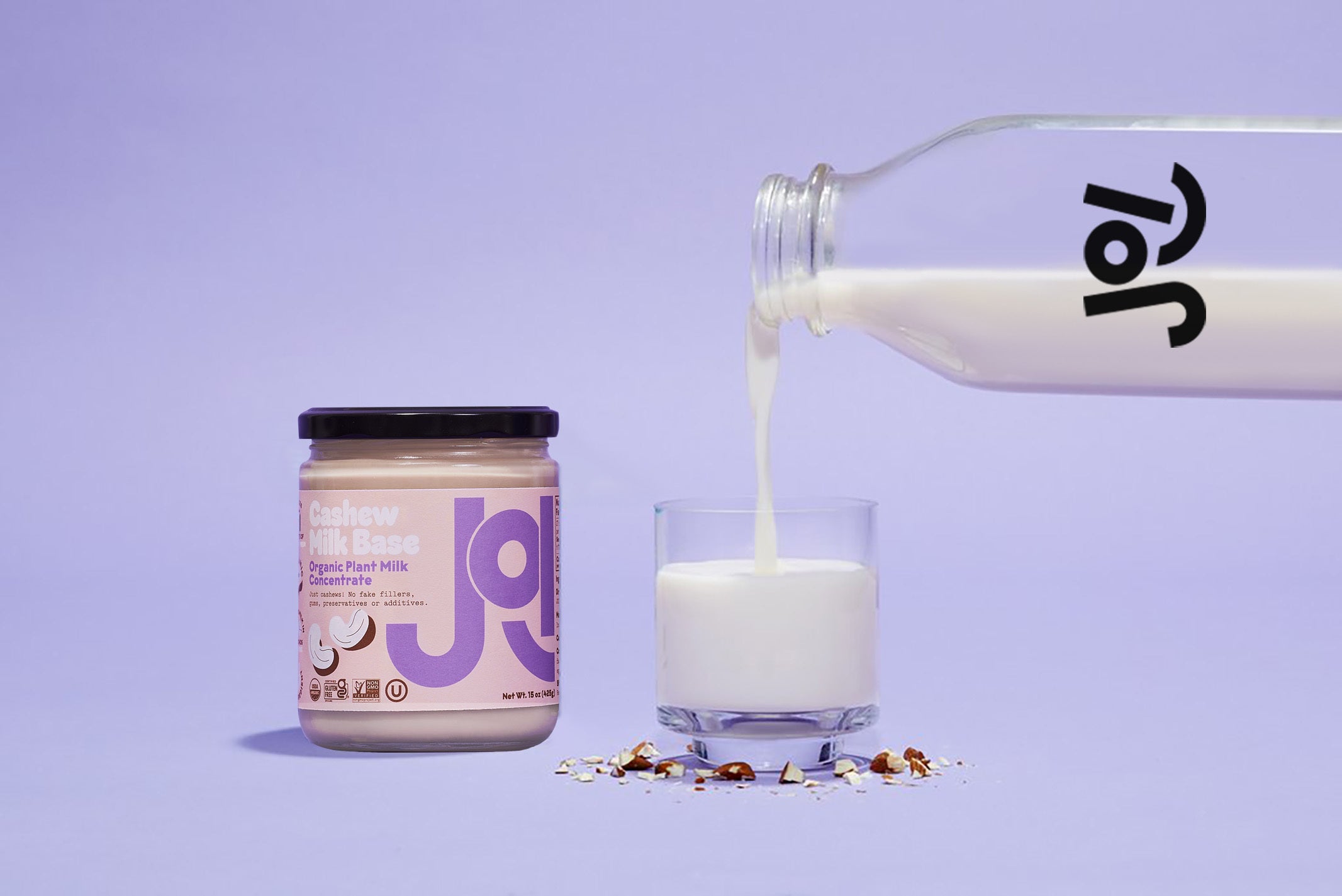 A jar of JOI Cashew Milk Base and a bottle of prepared JOI milk pouring into a glass.
