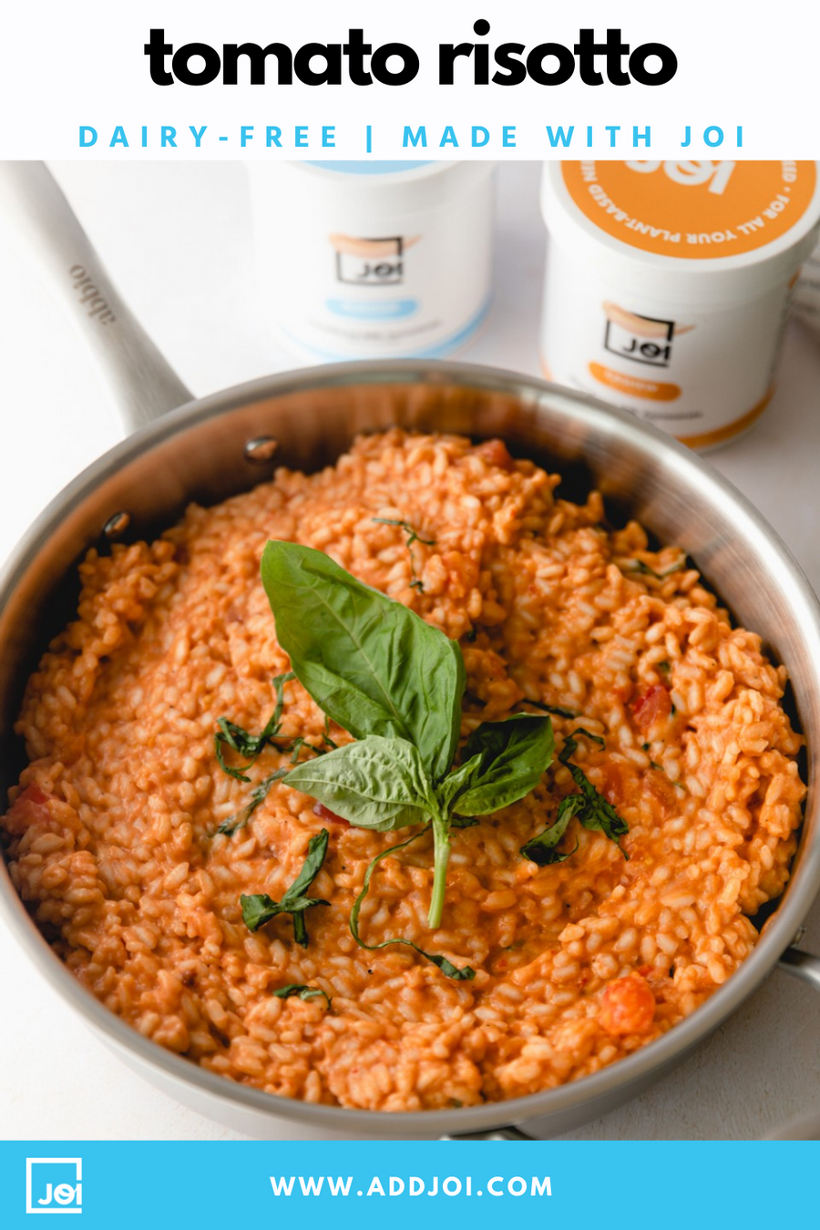 A stainless steel pot filled with creamy tomato risotto, garnished with fresh basil, next to two tubs of JOI plant bases.