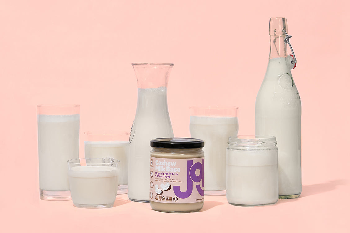 different plant milk and milk in pitchers and glasses with a jar of JOI