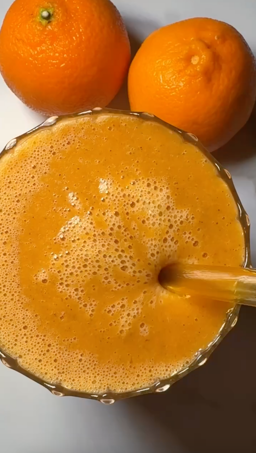 Orange juice with JOI concentrate being poured into a glass, surrounded by fresh oranges.