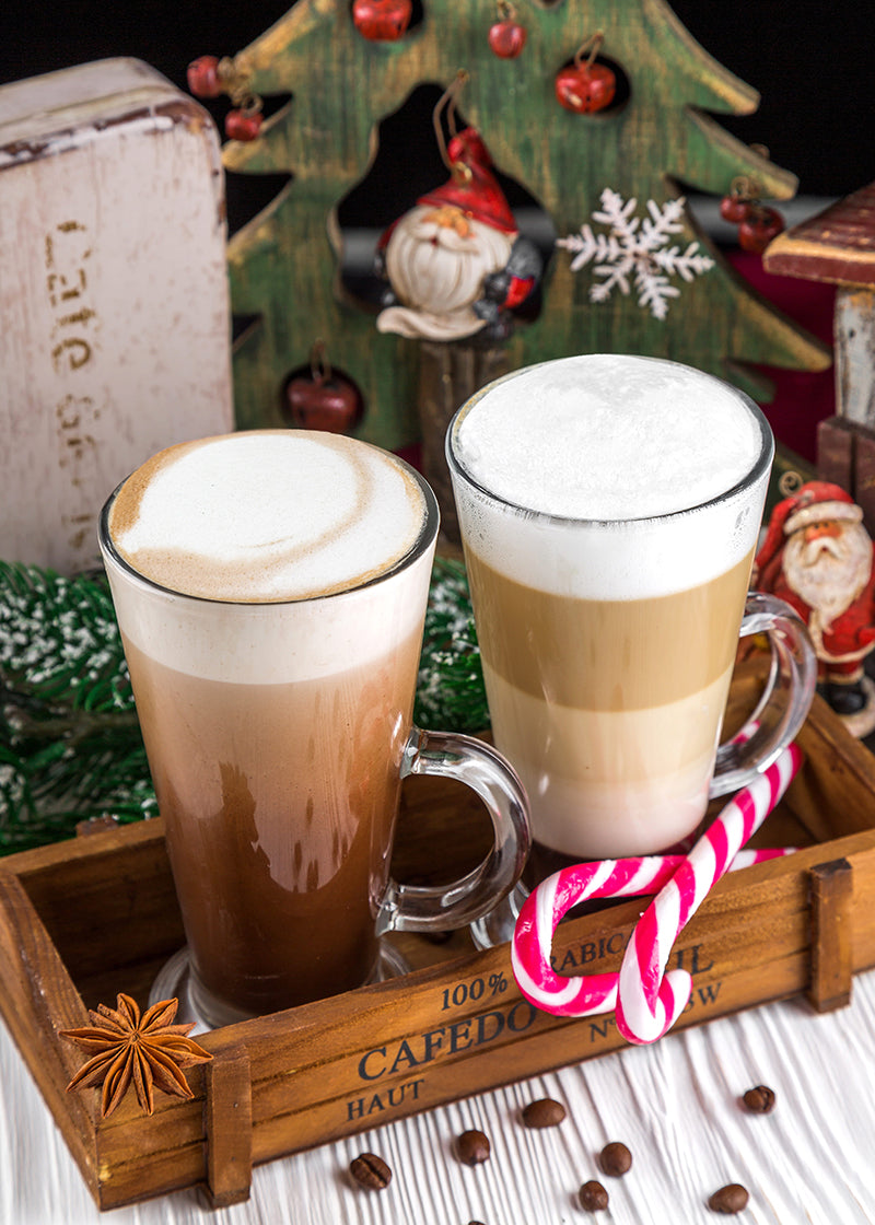 Two tall glasses of coffee with JOI eggnog creamer, garnished with a candy cane and star anise, for the holidays.
