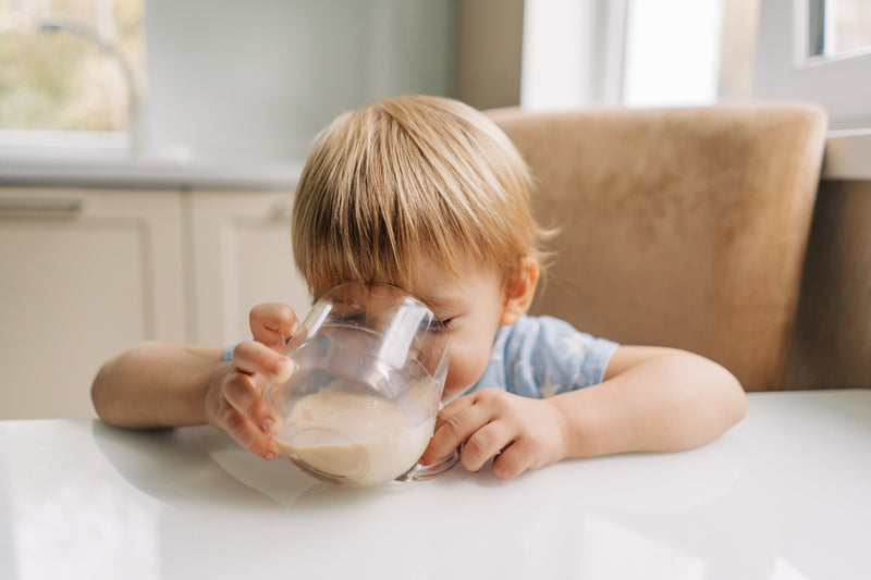 Child drinking plant-based milk from a glass, highlighting nutritious dairy-free options for growing kids.