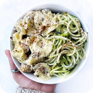 A photo of a bowl of zucchini pasta topped with a creamy sauce made with JOI Bases